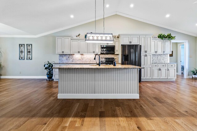 kitchen featuring a kitchen island with sink, hardwood / wood-style flooring, ornamental molding, tasteful backsplash, and stainless steel appliances