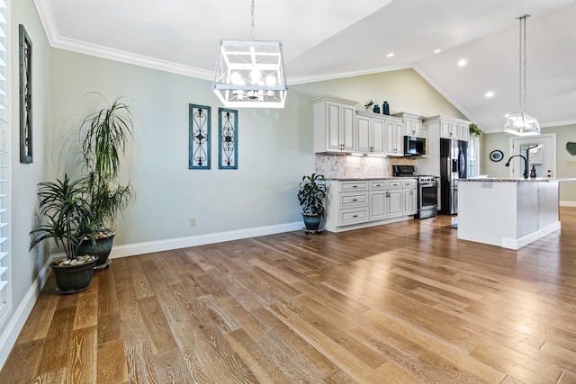 kitchen with white cabinets, ornamental molding, stainless steel appliances, and light hardwood / wood-style flooring