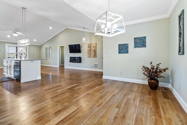 unfurnished living room with sink, wood-type flooring, lofted ceiling, and ornamental molding