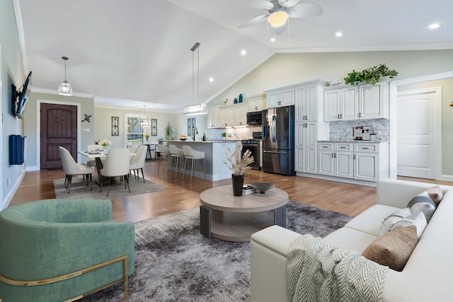 living room with ceiling fan, crown molding, dark wood-type flooring, and vaulted ceiling