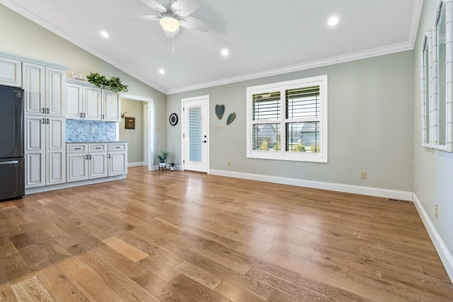 unfurnished living room with crown molding, ceiling fan, lofted ceiling, and light wood-type flooring