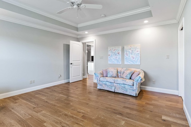 sitting room with a tray ceiling, hardwood / wood-style flooring, and ornamental molding