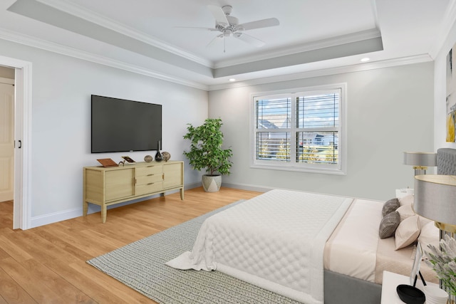 bedroom with wood-type flooring, a tray ceiling, ceiling fan, and crown molding