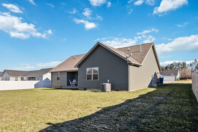 rear view of property featuring central air condition unit and a lawn