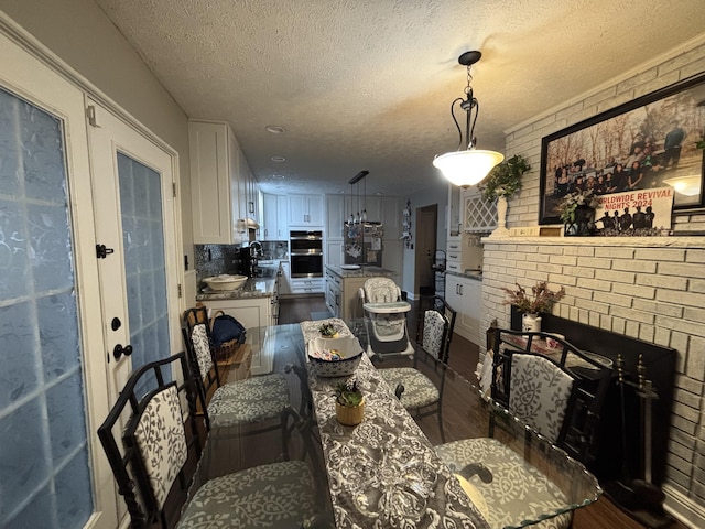 dining area featuring dark wood-type flooring, brick wall, sink, and a textured ceiling