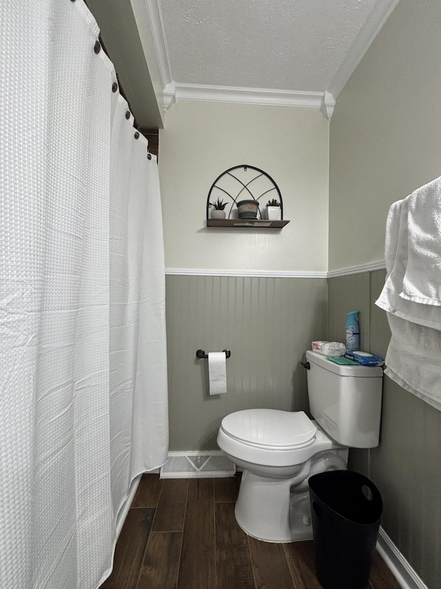 bathroom featuring ornamental molding, toilet, and a textured ceiling