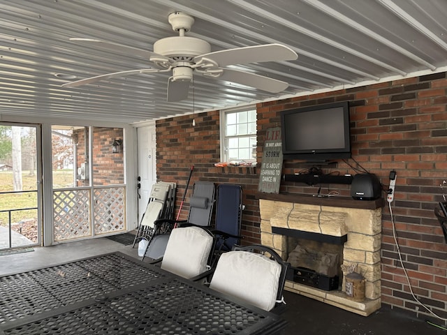 sunroom / solarium with a stone fireplace and ceiling fan