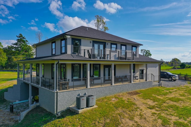 rear view of house featuring a lawn, cooling unit, a balcony, and french doors