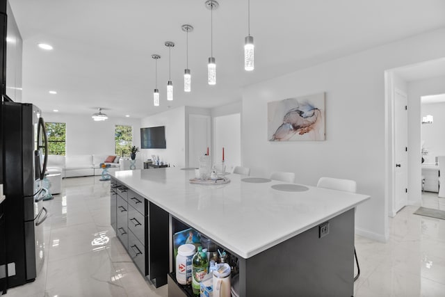 kitchen featuring a kitchen breakfast bar, black refrigerator, a center island, and hanging light fixtures