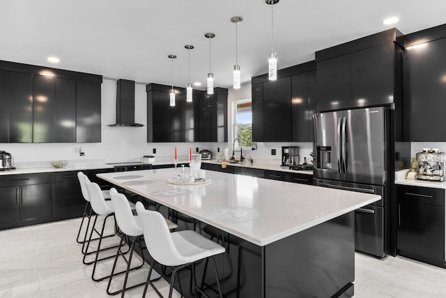 kitchen featuring sink, a center island, hanging light fixtures, wall chimney range hood, and stainless steel refrigerator with ice dispenser