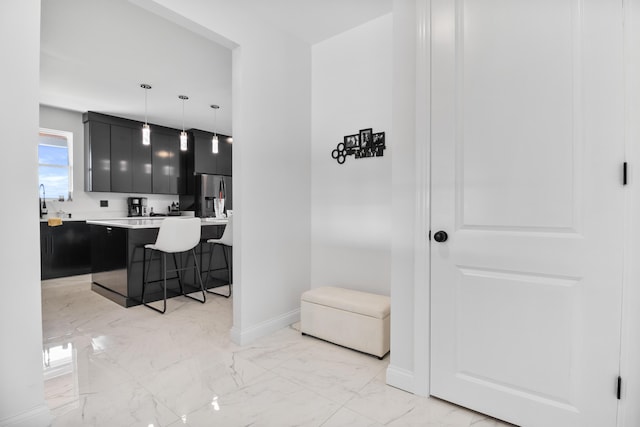 kitchen featuring stainless steel fridge, a breakfast bar, a center island, and hanging light fixtures