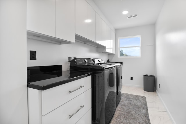 clothes washing area with cabinets and washing machine and clothes dryer