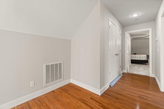 corridor with wood-type flooring and lofted ceiling