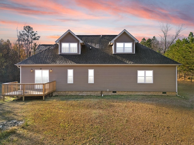 back house at dusk featuring a deck and a yard