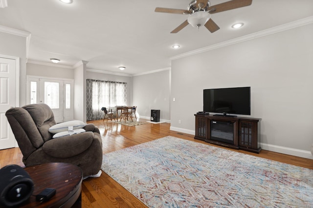 living room with ceiling fan, wood-type flooring, and ornamental molding