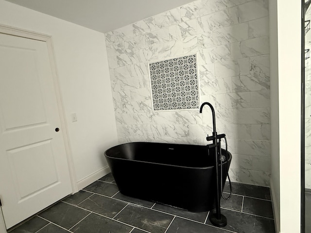 full bathroom with a freestanding tub and tile walls