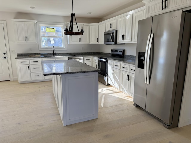 kitchen featuring light wood-type flooring, white cabinets, stainless steel appliances, and a sink