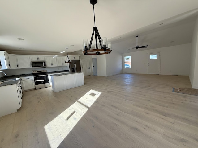 kitchen featuring stainless steel appliances, dark countertops, open floor plan, and a sink