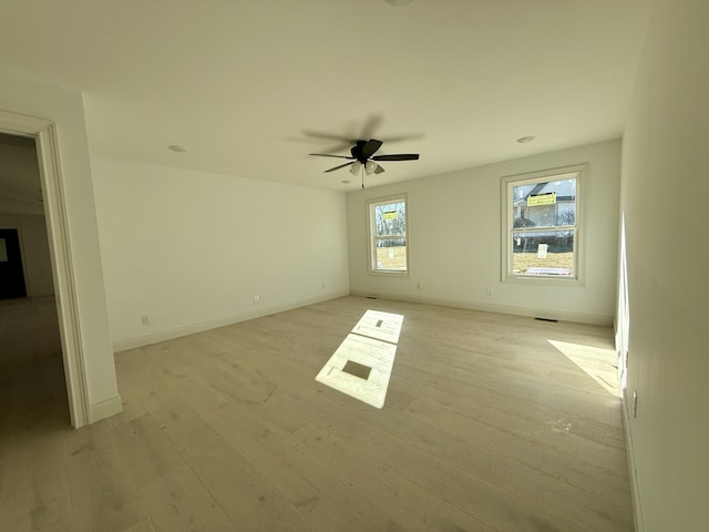 empty room with light wood-style floors, visible vents, ceiling fan, and baseboards