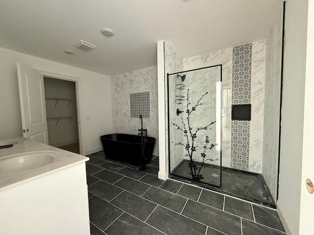 bathroom featuring vanity, visible vents, a spacious closet, a soaking tub, and a stall shower