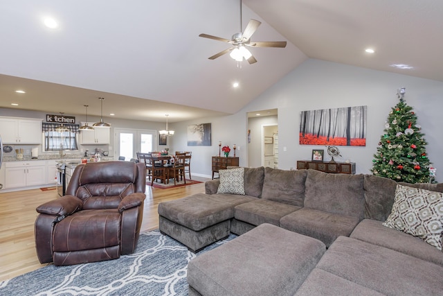 living room with light wood-type flooring, high vaulted ceiling, ceiling fan, and sink