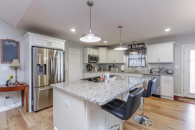 kitchen featuring a kitchen island, a healthy amount of sunlight, appliances with stainless steel finishes, and light hardwood / wood-style flooring