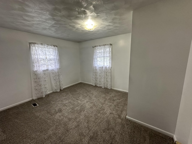 spare room with carpet flooring, visible vents, and baseboards