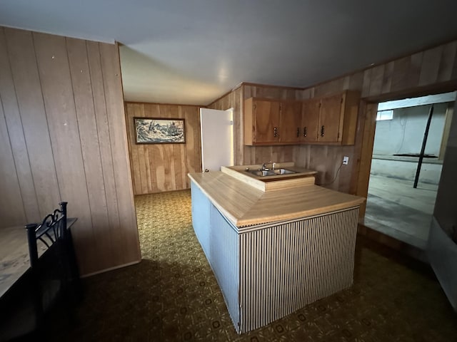 kitchen with light countertops, wood walls, and a sink