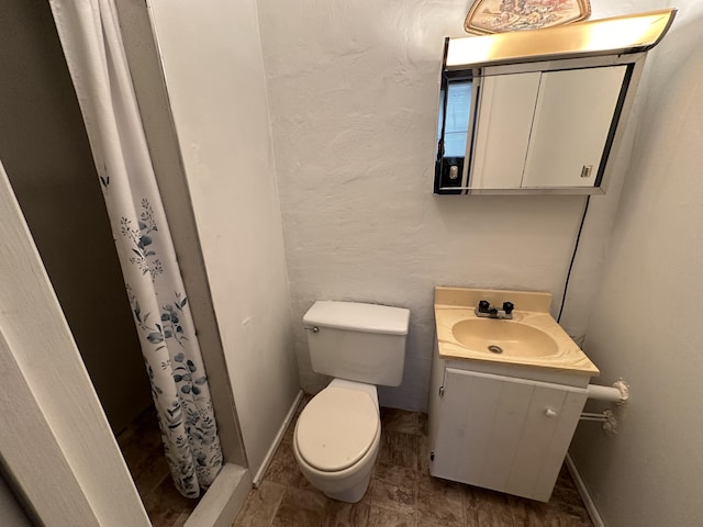 bathroom featuring baseboards, a textured wall, toilet, a shower with curtain, and vanity