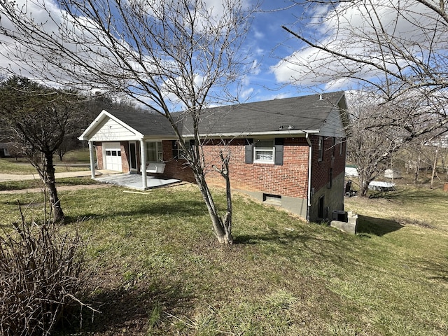 exterior space with a front yard, brick siding, and a patio