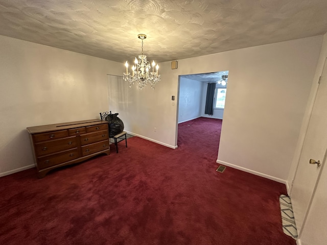 interior space with a chandelier, a textured ceiling, carpet floors, visible vents, and baseboards