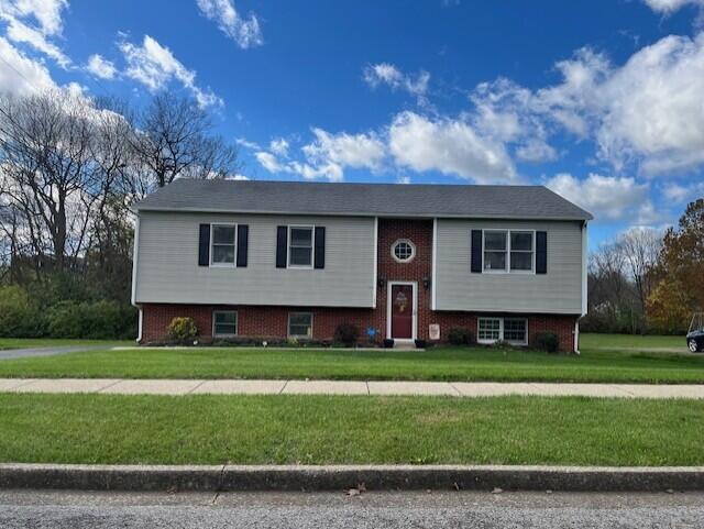 split foyer home with a front lawn and brick siding