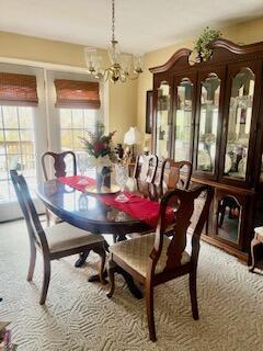 carpeted dining room with an inviting chandelier