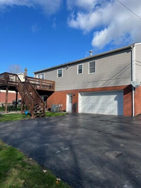 view of front of property featuring a garage, aphalt driveway, stairway, and brick siding