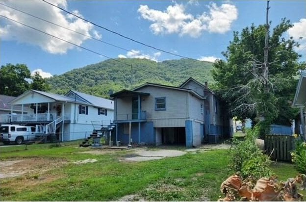 back of property with a mountain view and a yard