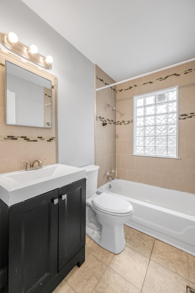 full bathroom featuring tile patterned floors, toilet, vanity, tile walls, and tiled shower / bath