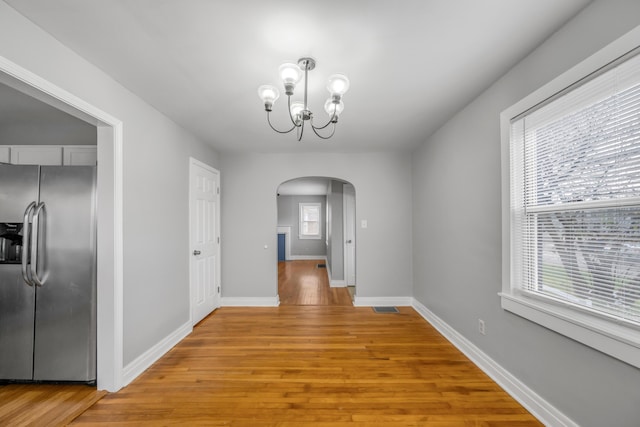 unfurnished dining area with a chandelier and light wood-type flooring