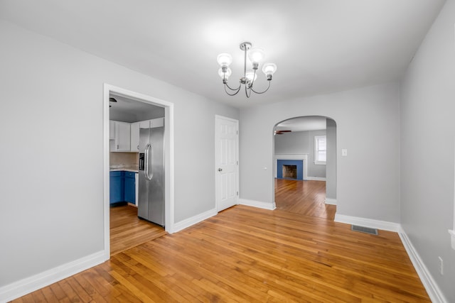 unfurnished dining area with ceiling fan with notable chandelier and light hardwood / wood-style floors