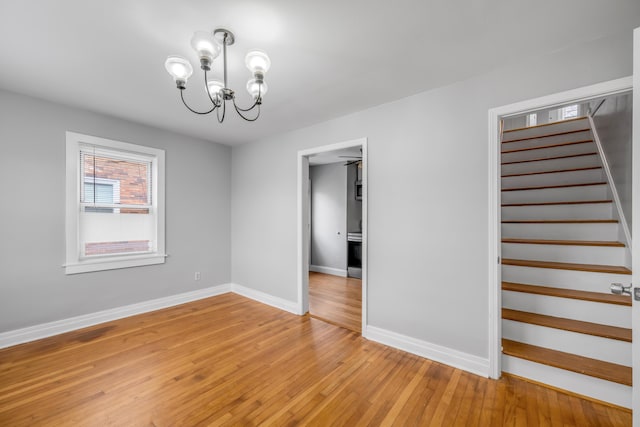 unfurnished room featuring a notable chandelier and light wood-type flooring