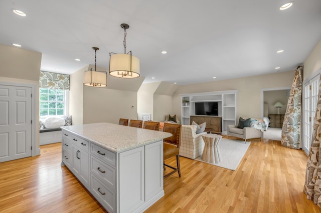 1821 Delong Rd, Lexington, KY 40515 - kitchen featuring hanging light fixtures, light wood-style flooring, light stone counters, a breakfast bar, and a kitchen island