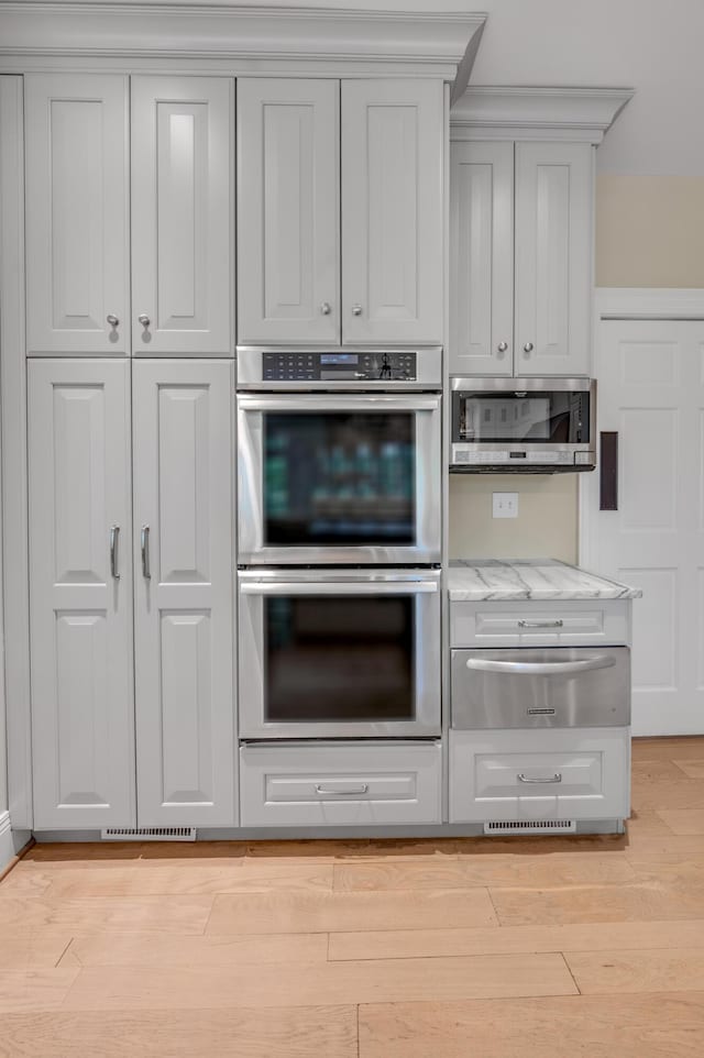 1821 Delong Rd, Lexington, KY 40515 - kitchen with a warming drawer, light stone counters, light wood-style flooring, and appliances with stainless steel finishes