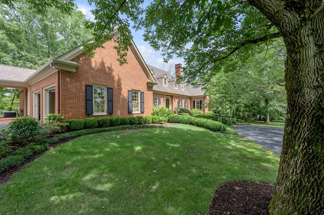 1821 Delong Rd, Lexington, KY 40515 - view of home's exterior featuring a chimney, brick siding, a yard, and central air condition unit