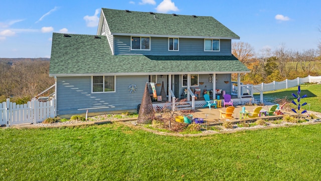 rear view of house featuring a porch, a yard, and a shingled roof