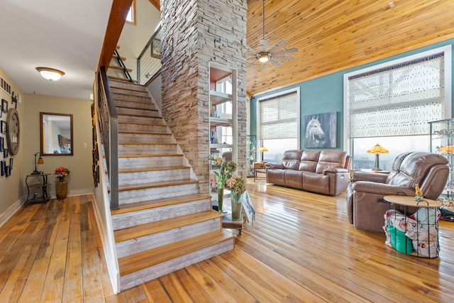 stairs with baseboards, a towering ceiling, and hardwood / wood-style floors