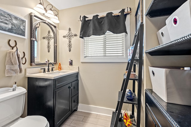 half bath with vanity, toilet, and baseboards