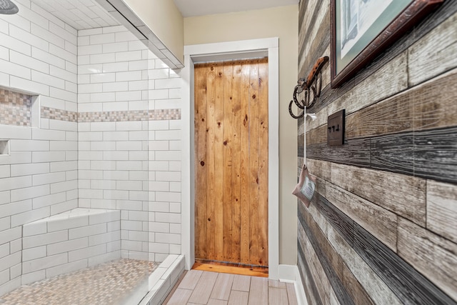 bathroom with tiled shower and wood finished floors