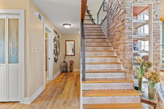 stairway with baseboards, wood-type flooring, and visible vents