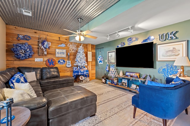 living area with track lighting, visible vents, wood walls, and ceiling fan