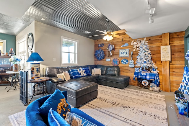 living room with wooden walls, rail lighting, and a ceiling fan