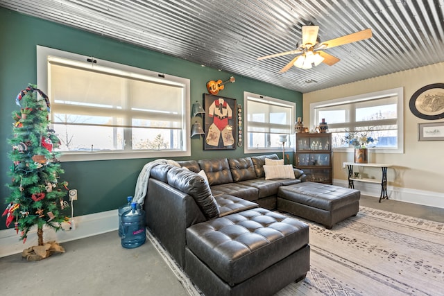 living area featuring baseboards, concrete flooring, and ceiling fan